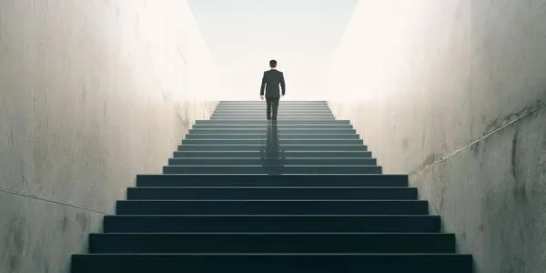 A man is walking up some stairs in the light